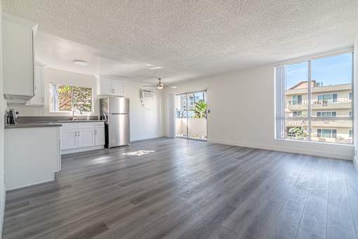 A spacious living room with a kitchen area and hardwood flooring.