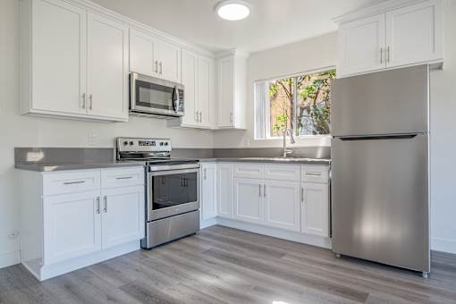 A kitchen with white cabinets and a stainless steel refrigerator.