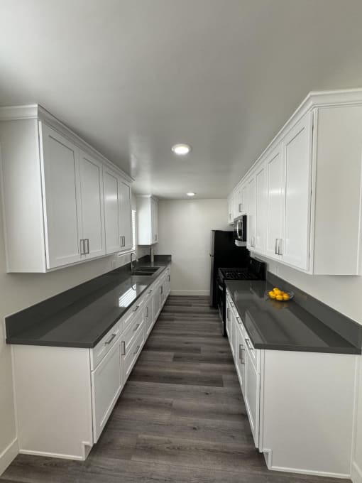 a white kitchen with black counter tops and white cabinets
