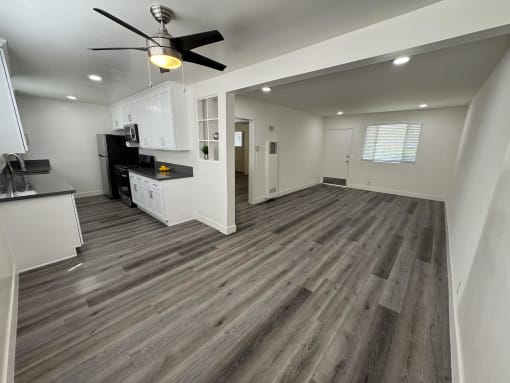 a renovated living room and kitchen with hardwood floors and a ceiling fan