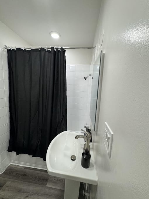 a bathroom with a sink and a shower with a black shower curtain