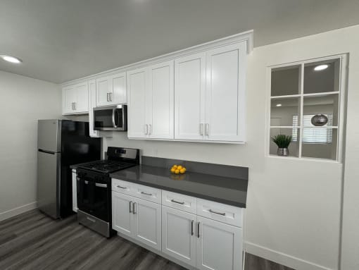 a kitchen with white cabinets and a black counter top