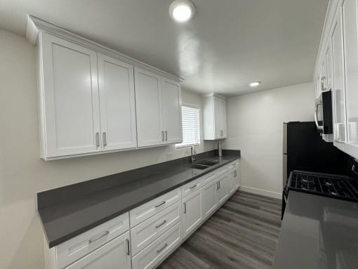 a kitchen with white cabinets and black counter tops