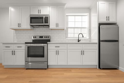 A modern kitchen with white cabinets and stainless steel appliances.