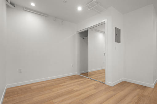 A room with a wooden floor and a mirror on the wall.