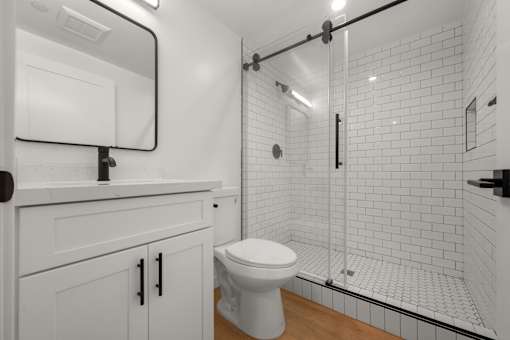 A white toilet sits in a bathroom with a walk-in shower.