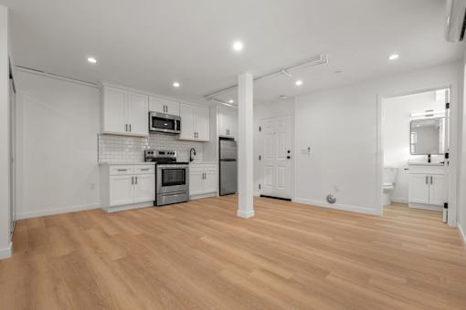 A kitchen with white cabinets and a wooden floor.