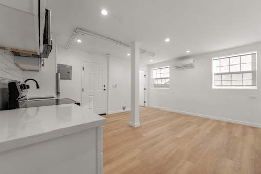 A kitchen with white countertops and wooden floors.