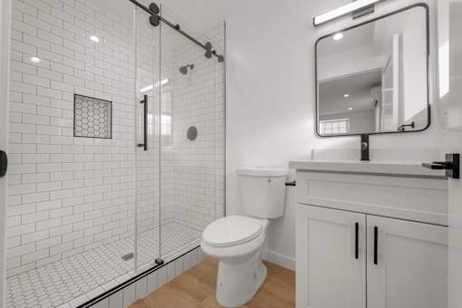 A white toilet in a bathroom with a white tiled shower.