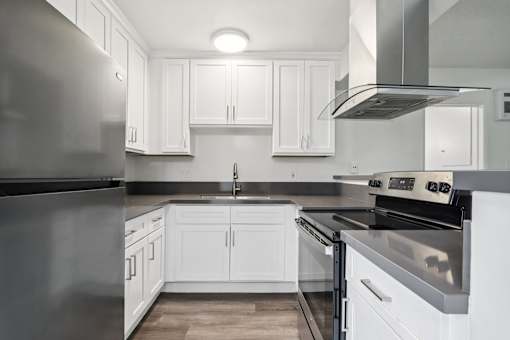 A modern kitchen with white cabinets and stainless steel appliances.