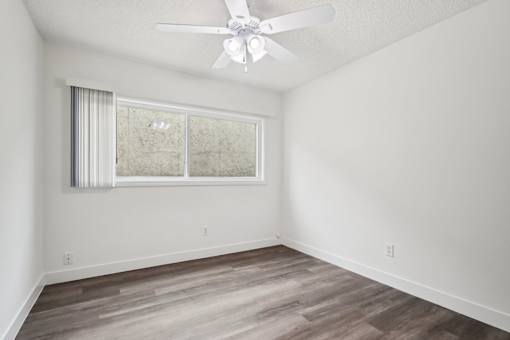 A room with a ceiling fan and a window with blinds.