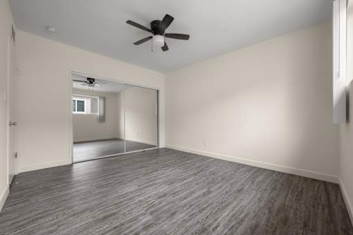 A room with a ceiling fan and wood flooring.