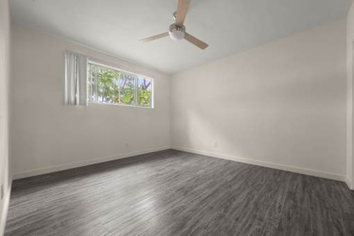 an empty living room with a ceiling fan and a window