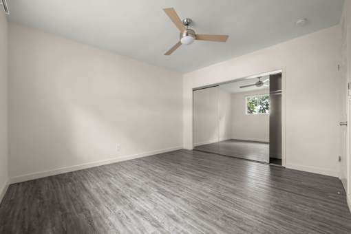 an empty living room with white walls and a ceiling fan