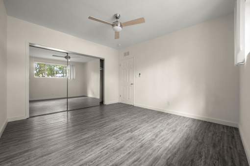 an empty living room with a ceiling fan and a window