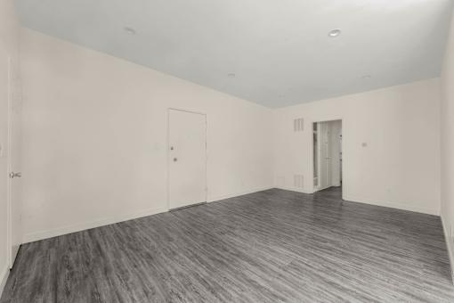 the living room of a house with white walls and wood floors