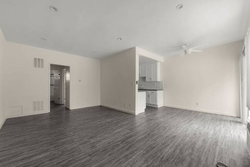 the living room and kitchen of an empty house with wood floors