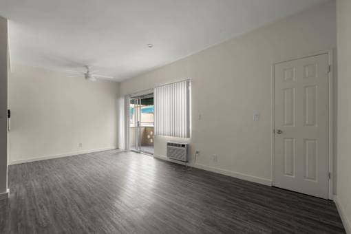the living room and dining room of an empty home with a door to a balcony