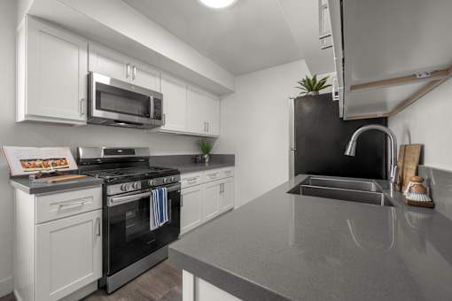 A kitchen with a black countertop and white cabinets at Sunset Square, West Covina, 91790