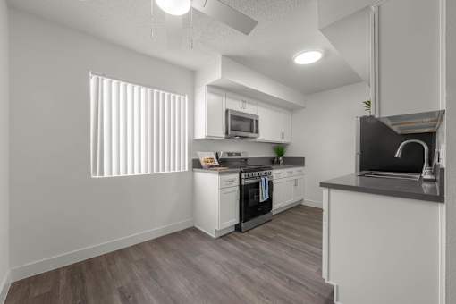 A modern kitchen with white cabinets and a wooden floor at Sunset Square, West Covina, 91790