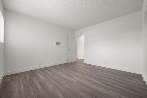 A room with wooden flooring and white walls at Sunset Square, West Covina, 91790