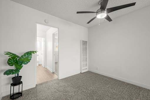 A room with a ceiling fan and a potted plant on a stand at Sunset Square, West Covina, 91790