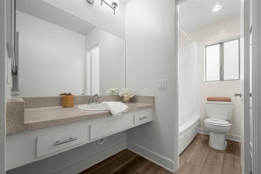 A bathroom with a sink, mirror, and toilet at Sunset Square, West Covina, 91790