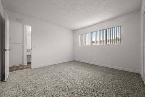 A room with a carpeted floor and a window with blinds at Sunset Square, West Covina, 91790