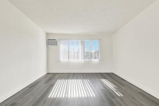 A room with a window and a wooden floor.