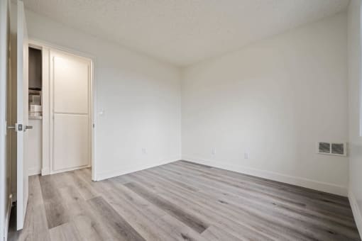 a spacious bedroom with white walls and wood floors at Monterra Ridge Apartments, Canyon Country, California