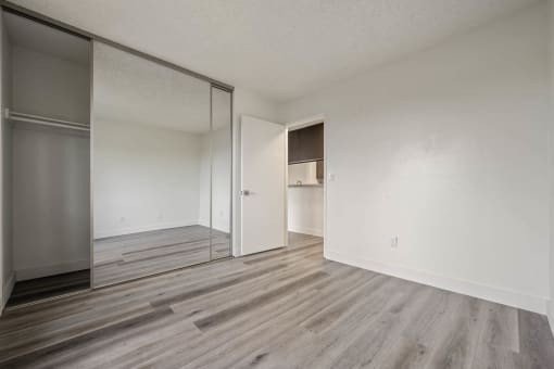 Spacious bedroom with wood flooring and a mirrored closet at Monterra Ridge Apartments, Canyon Country, CA