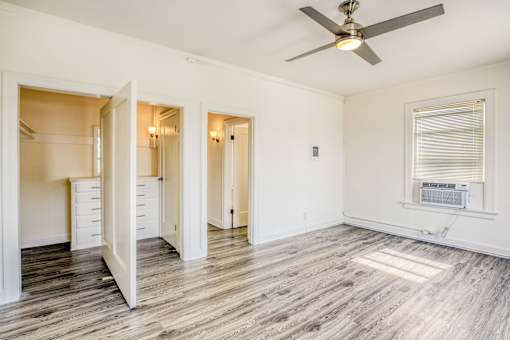A room with a ceiling fan and a window with blinds.