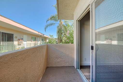 A balcony with a glass door leading to a house.