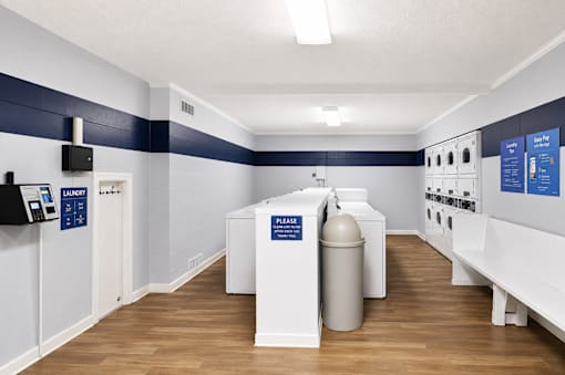 A room with a white and blue color scheme has a white sink and a white trash can.