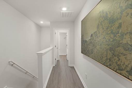 A hallway with a painting on the wall and a staircase on the left.
