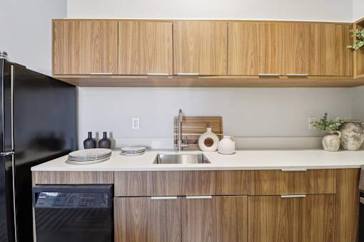 A kitchen with wooden cabinets and a black refrigerator.