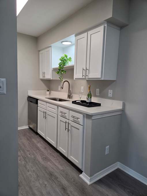 A kitchen with white cabinets and a black countertop.