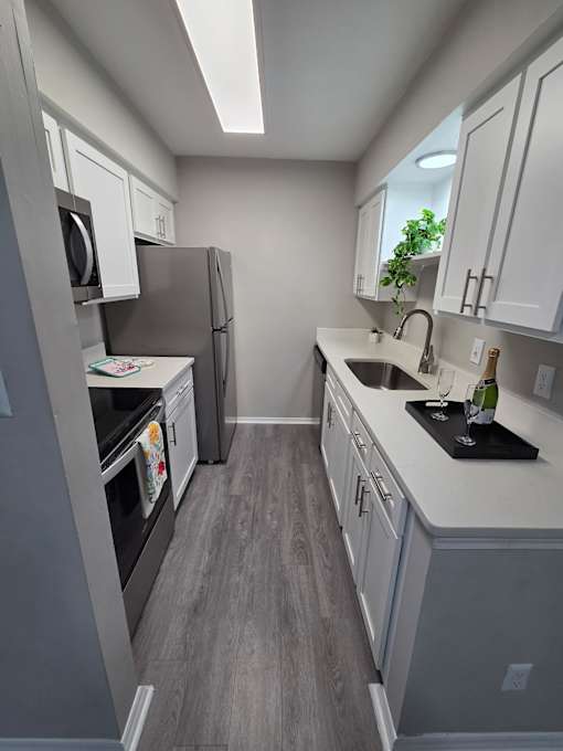 A kitchen with a refrigerator, oven, and sink.