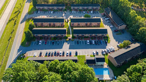 An aerial view of a parking lot with a swimming pool and a building.