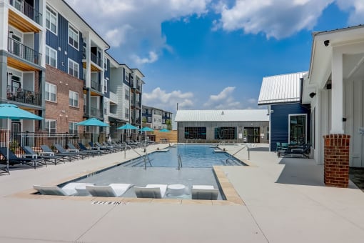a swimming pool with lounge chairs and umbrellas in front of an apartment building in Asheville NC