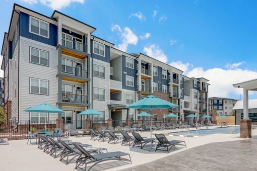 an outdoor swimming pool with chaise lounge chairs and umbrellas in front of an apartment in Asheville NC