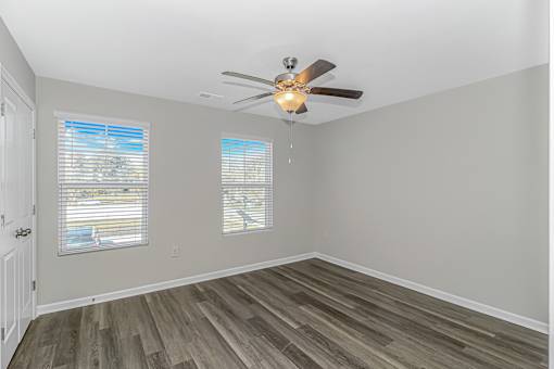 A room with a ceiling fan and wooden flooring.