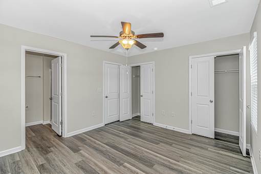 A room with a ceiling fan and wood flooring.