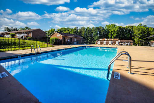 A swimming pool with a ladder and a sunny sky.
