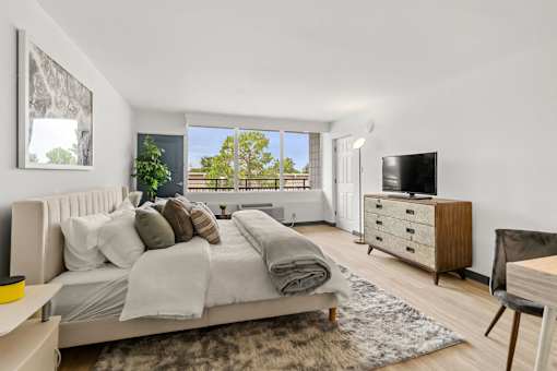 A bedroom with a large bed, a chair, and a TV.