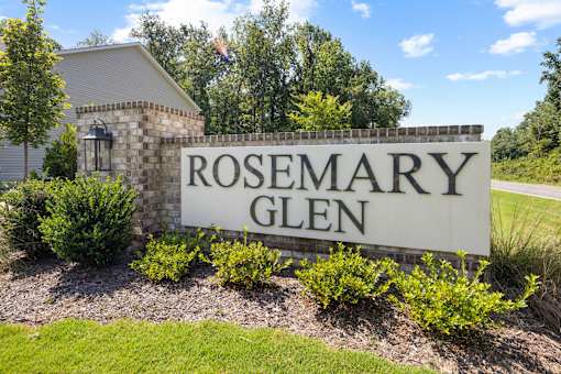 A sign that says "ROSEMARY GLEN" in front of a building.