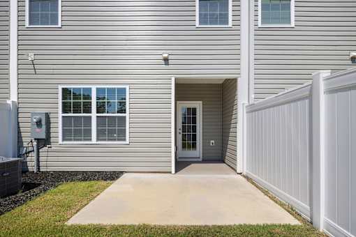 A grey house with a white fence and a grey door.