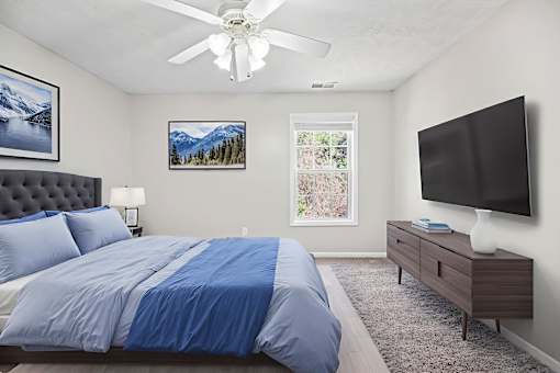 A bedroom with a bed, a dresser, a ceiling fan, and a window.