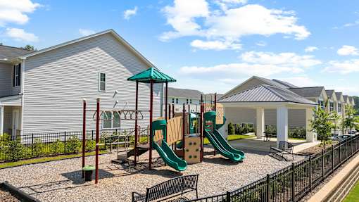 A playground with a green slide and a red pole.