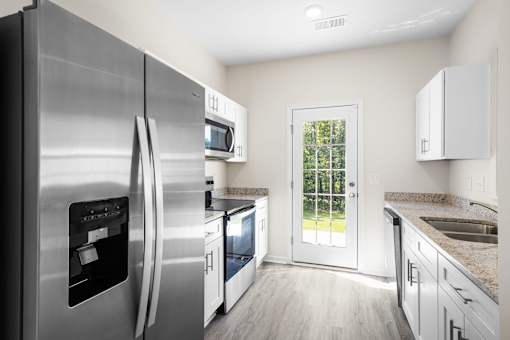 A modern kitchen with a stainless steel refrigerator and white cabinets.